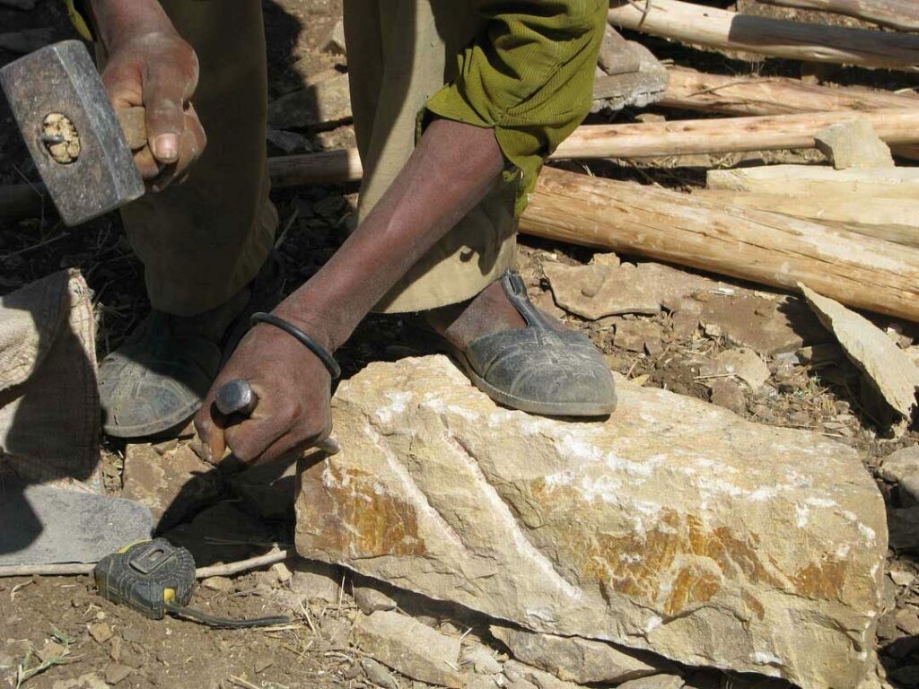 A man chiseling a brick by hand