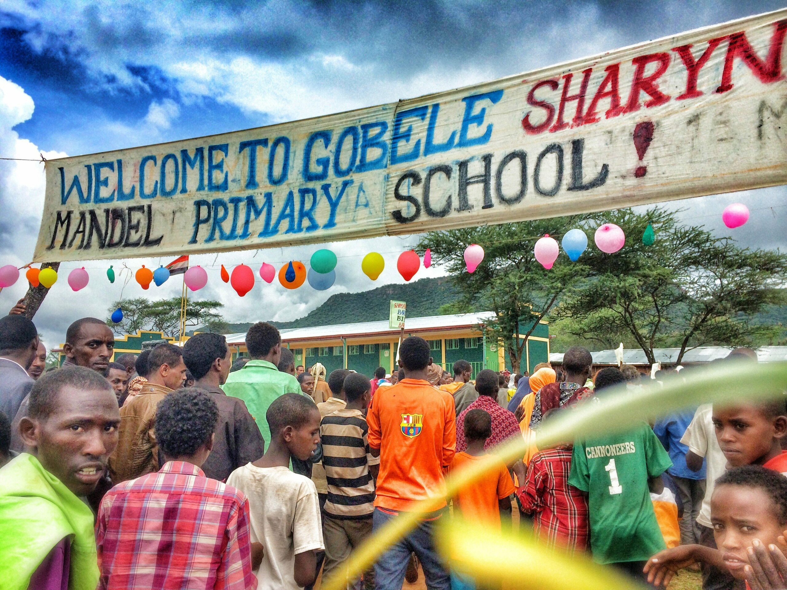 A group of people standing under a welcome sign at Gobele Sharyn Primary School