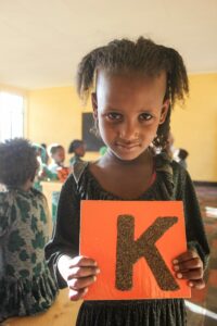 A young girl practices the alphabet in her new early childhood education classroom.